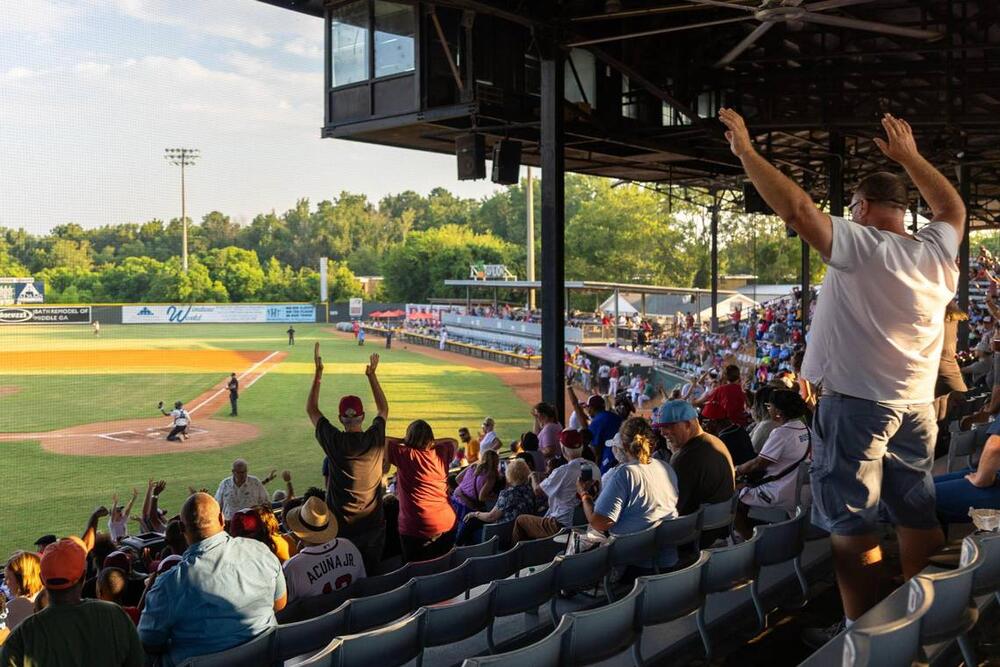 Attendees stand up and wave their arms during a free t-shirt toss between innings during the Coastal Plains League All-Star Game on Monday, July 7, 2025, at Luther Williams Field in Macon, Georgia. The best players from across the summer collegiate baseball league, which includes the Macon Bacon, came to Macon for a two-day showcase. Carly Lenhardt/The Telegraph