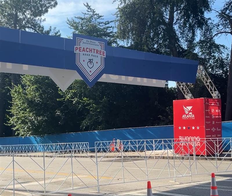 A big blue arch with a white shield that says " Atlanta Journal Constitution Peachtree Road Race"