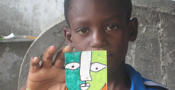 A Haitian student from Project Hope ART holds up his artwork. (Photo courtesy Karen Packer.)