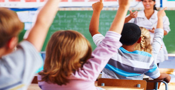 Children raising their hands in a classroom.