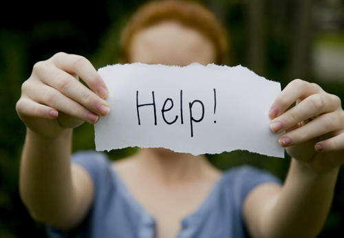 A pair of hands hold out a paper that says "help" 