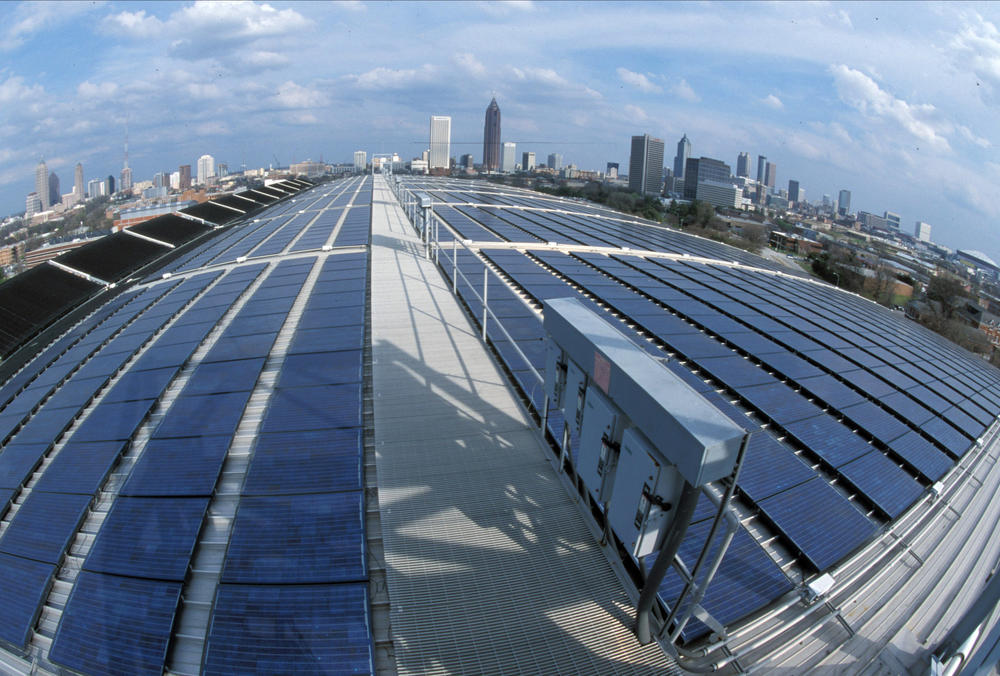 Solar panels are seen atop the Georgia Tech Aquatic Center with the Atlanta skyline in the distance.