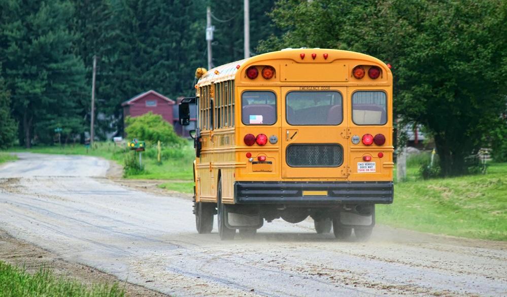 A school bus rolls down a rural road.