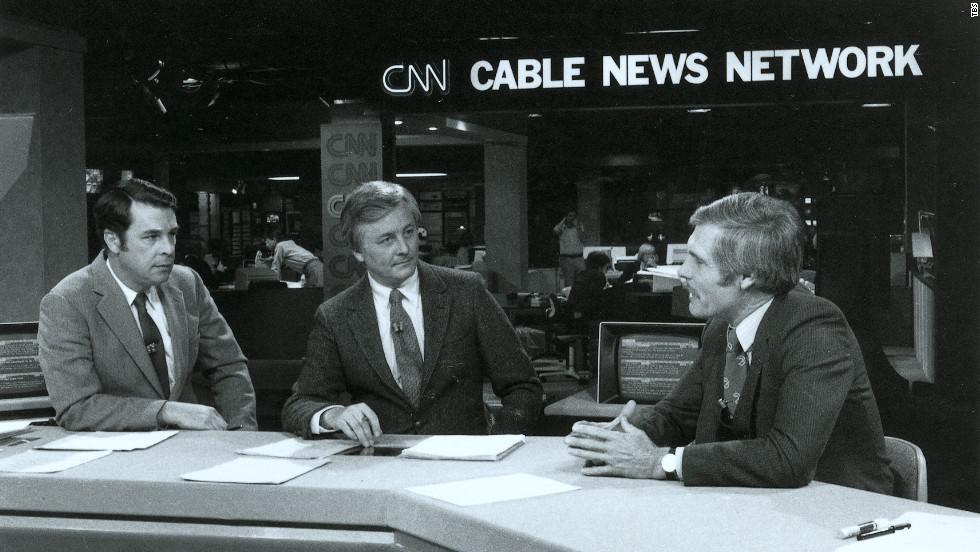 Ted Turner (right) speaks with anchors before a CNN newscast during the 1980s.
