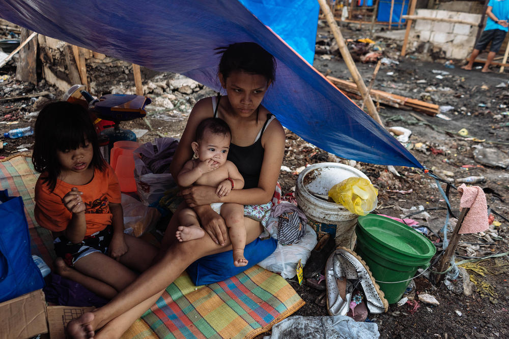 Joy Villanueva, 15, holds her baby. The slums where her family lived had burned down; they hope to build a new shack to replace the home they lost.