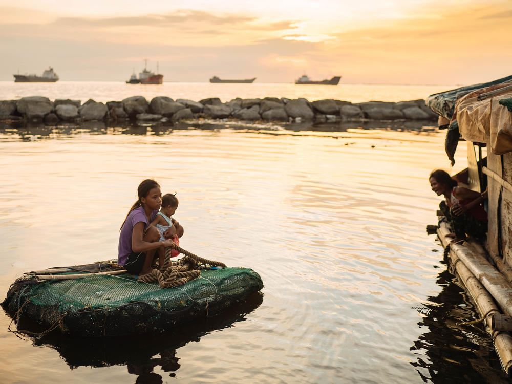 Joan Garcia became pregnant at 14 and gave birth at 15. She and her child travel by raft between the two shacks where they live in Navotas fish port on Manila Bay.