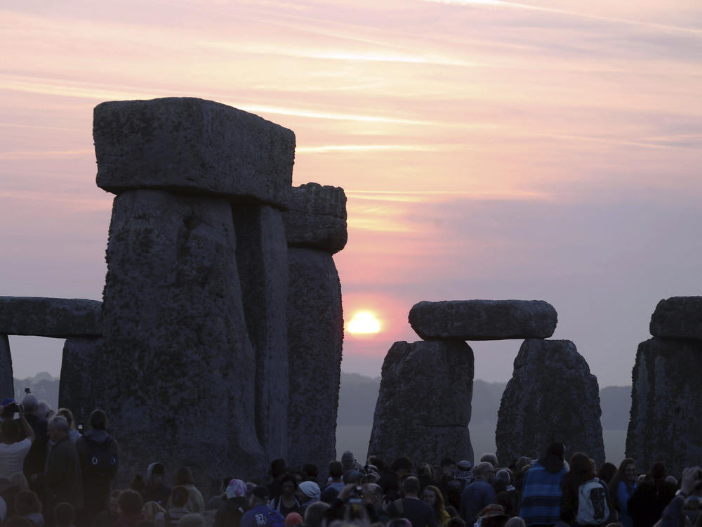 Thousands of people stand among the ancient stones at Stonehenge in Salisbury, England, at sunrise on the summer solstice. Archaeologists on Monday announced the discovery of a ring of shafts about 2 miles away.