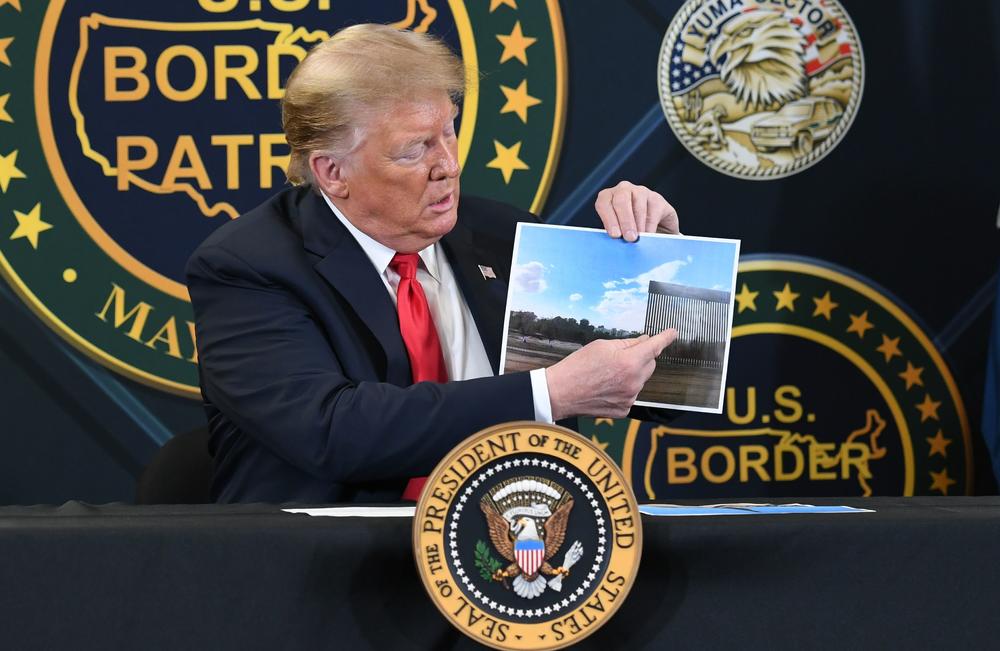 President Trump shows a photo of the wall along the southern border during a roundtable briefing on border security Tuesday in Yuma, Ariz.