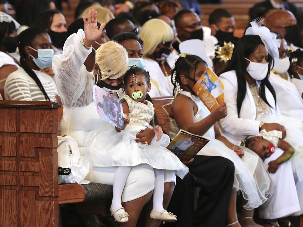 Tomika Miller, the widow of Rayshard Brooks, raises her hand heavenly while holding their 2-year-old daughter Memory during a funeral prayer at Ebenezer Baptist Church.
