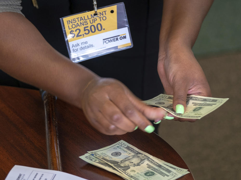 A manager of a financial services store in Ballwin, Mo., counts cash being paid to a client as part of a loan in 2018. Consumer groups blasted a new payday lending rule and its timing during a pandemic that has put tens of millions of people out of work.