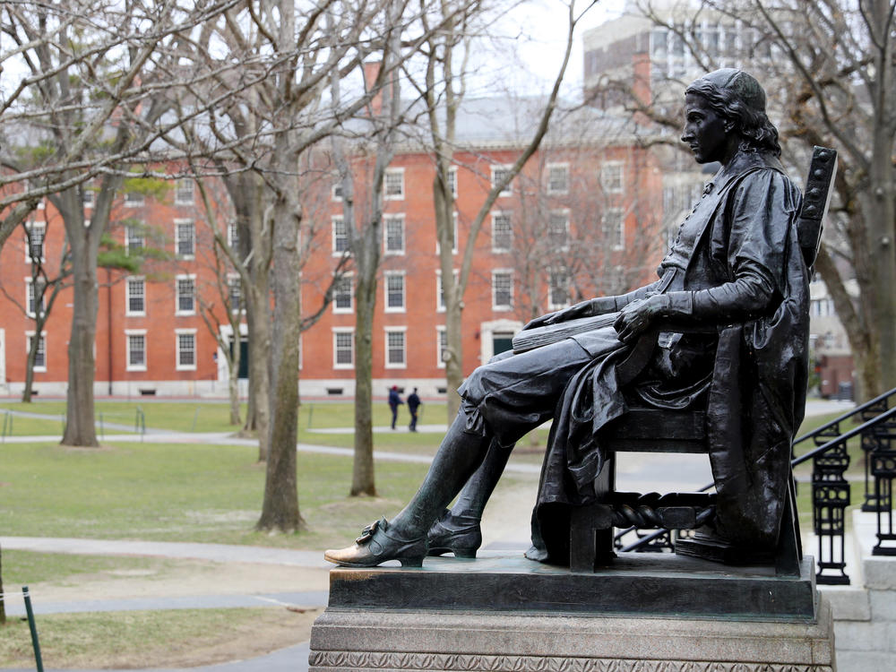 A statue of John Harvard, namesake of the university, overlooks the campus earlier this year. Harvard University joined the Massachusetts Institute of Technology in suing the federal government over its policies on international students Wednesday.