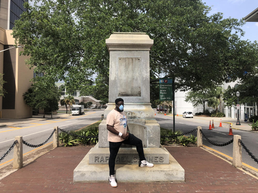 Protest organizer DAntjuan Miller stands by the granite pedestal that remains of a monument to Confederate Navy Adm. Raphael Semmes in Mobile, Ala. 