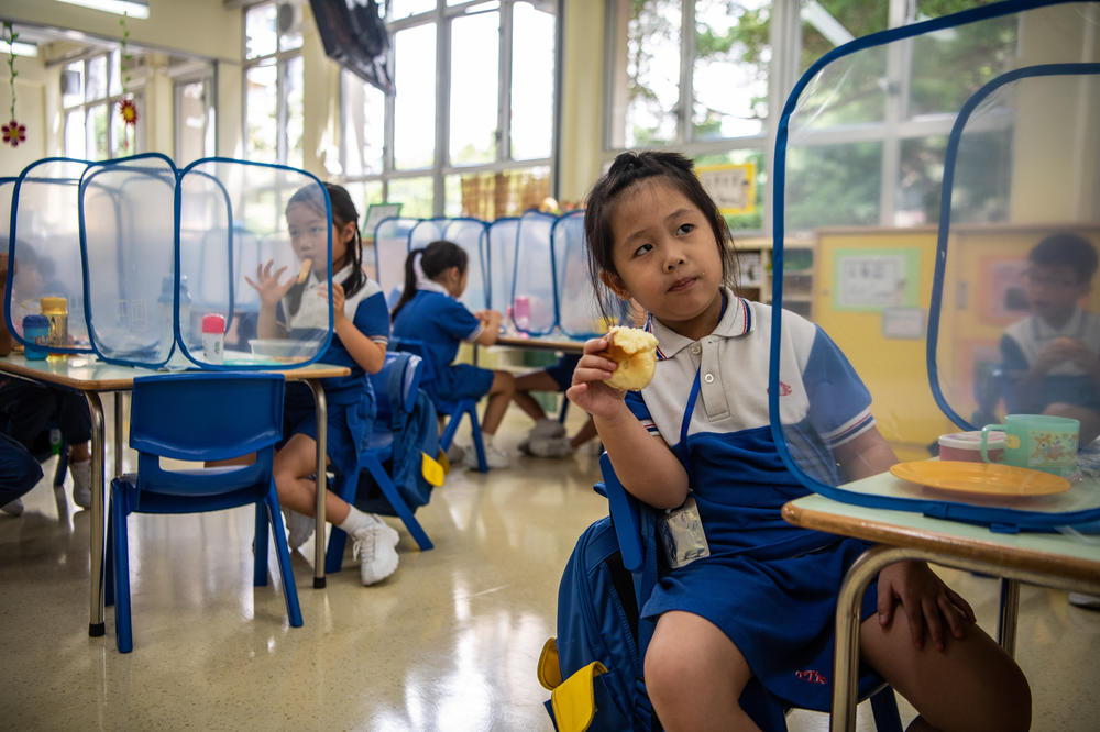 Kindergarten children eat their snacks behind plastic dividers at Tsung Tsin Primary School and Kindergarten.