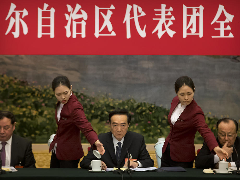 Attendants refill teacups as Chen Quanguo (center), Communist Party secretary of China's Xinjiang Uighur Autonomous Region, listens to a speaker during a group discussion meeting on the sidelines of the National People's Congress at the Great Hall of the People in Beijing, on March 12, 2019. The Politburo member is one of the subjects of new U.S. sanctions over human rights abuses in the region.