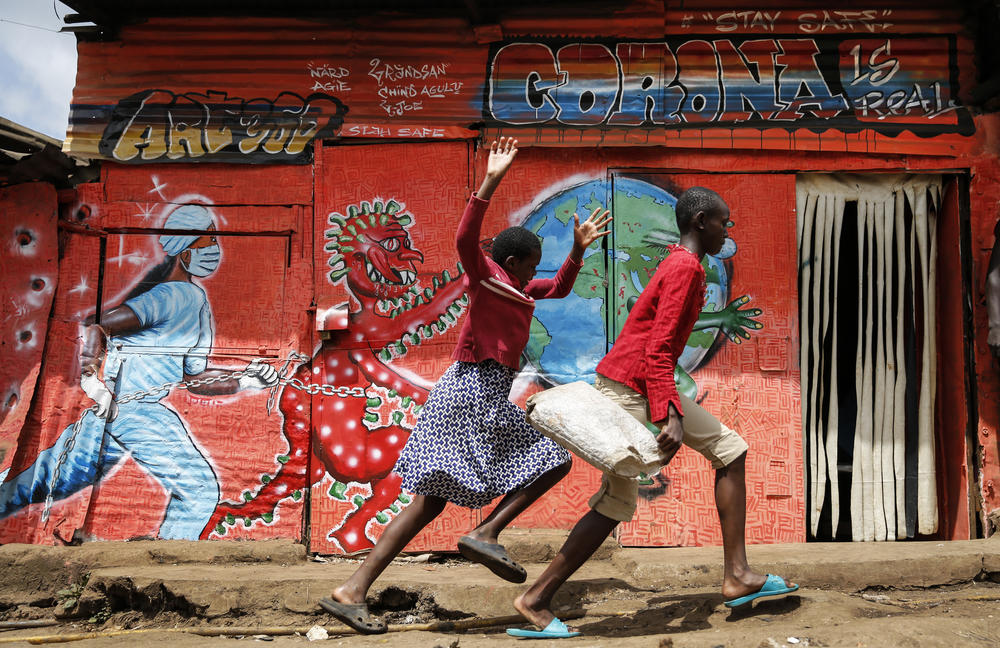 Children run down a street past an informational mural warning people about the dangers of the coronavirus in the Kibera settlement in Nairobi, Kenya, June 3.