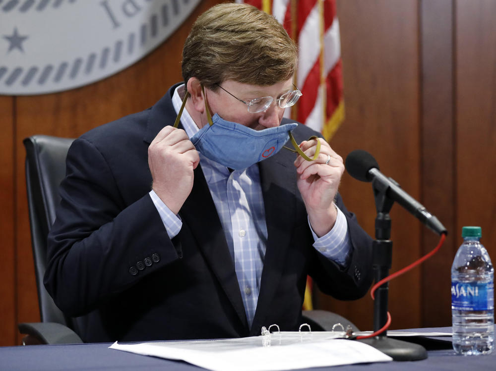 Mississippi Gov. Tate Reeves removes his face mask during a COVID-19 news briefing Wednesday in Jackson.