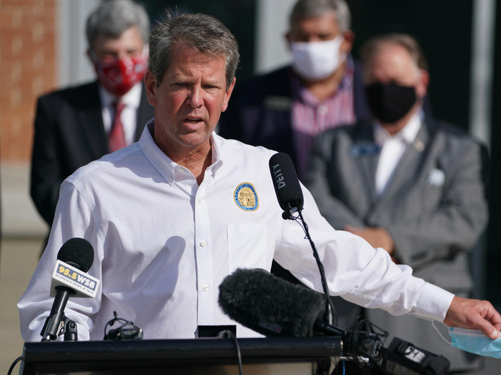 Georgia Gov. Brian Kemp holds a protective mask while speaking during a 'Wear A Mask' tour stop in Dalton, Georgia, earlier this month.