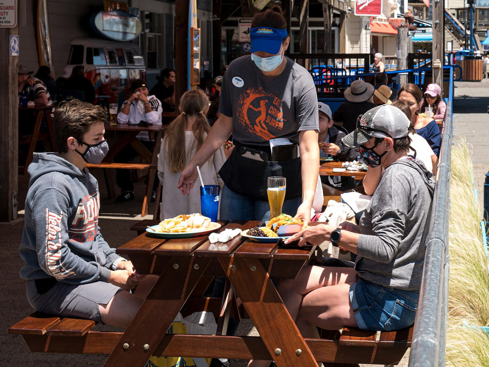Patrons wear masks as they sit on the outdoor patio of a restaurant on Pier 39 at Fisherman's Wharf in San Francisco. California is among more than 20 states that require face masks to help combat the spread of the coronavirus.