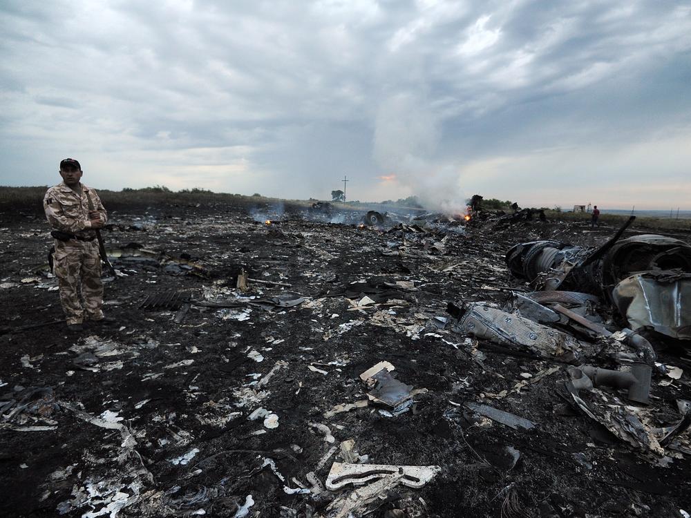 A man wearing military fatigues stands next to the wreckage of Malaysia Airlines MH17 carrying 298 passengers and crew, that crashed in eastern Ukraine six years ago.