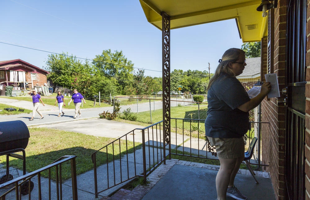 Sarah Sapp, a first year second grade teacher at Hartley Elementary School in Macon, leaves an informational flier in the door of the home of one of her students during a bus tour of the Hartley school district.