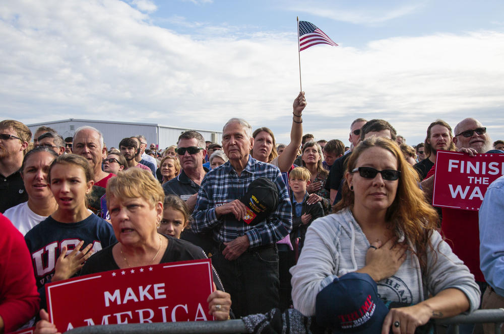 People gathered to hear President Trump campaign fo Georgia Republican gubernatorial candidate Brian Kemp pause for the National Anthem Sunday in Macon, Ga. 