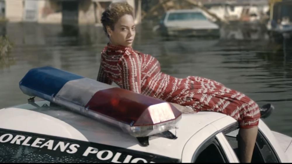 A scene from the Formation music video that shows BeyoncÃ© on a New Orleans police car in the aftermath of Hurricane Katrina.