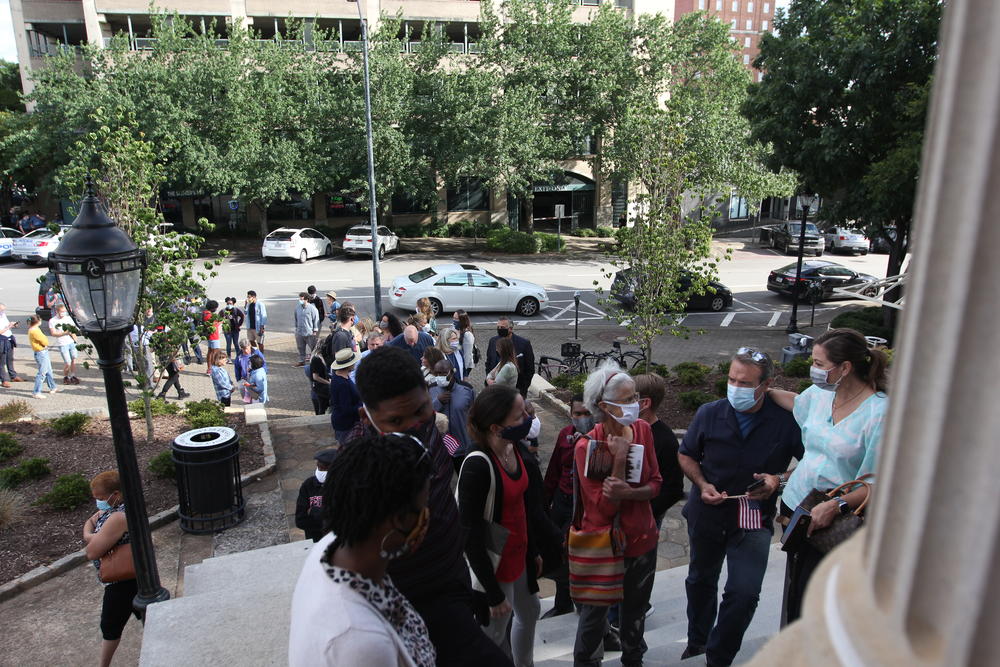 Athens-Clarke County residents wait in line at City Hall to provide public comment on the 2021 local government budget on June 16, 2020, in Athens, Georgia. People waited in line for hours as protesting and discussions regarding the reallocation of police department funds occurred around them. 