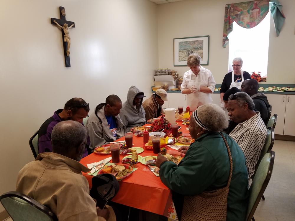 Diners pray with a volunteer before their Thanksgiving meal at Savannah's Social Apostolate.