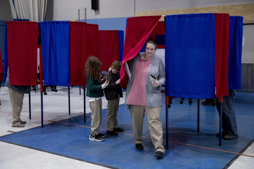 Samantha Murch, center, accompanied by her two boys Alexander, 8, and Jacob, 11, left, steps out of the voting booth for the New Hampshire primary at Bishop O'Neill Youth Center, Tuesday, Feb. 11, 2020, in Manchester, N.H. 