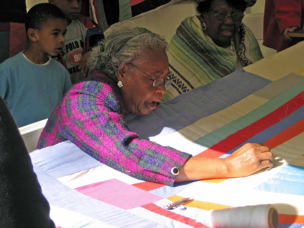 A member of the Gee's Bend stiching a new pattern into her quilt. 
