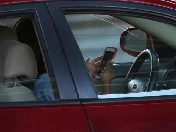 A driver uses a phone while behind the wheel of a car.