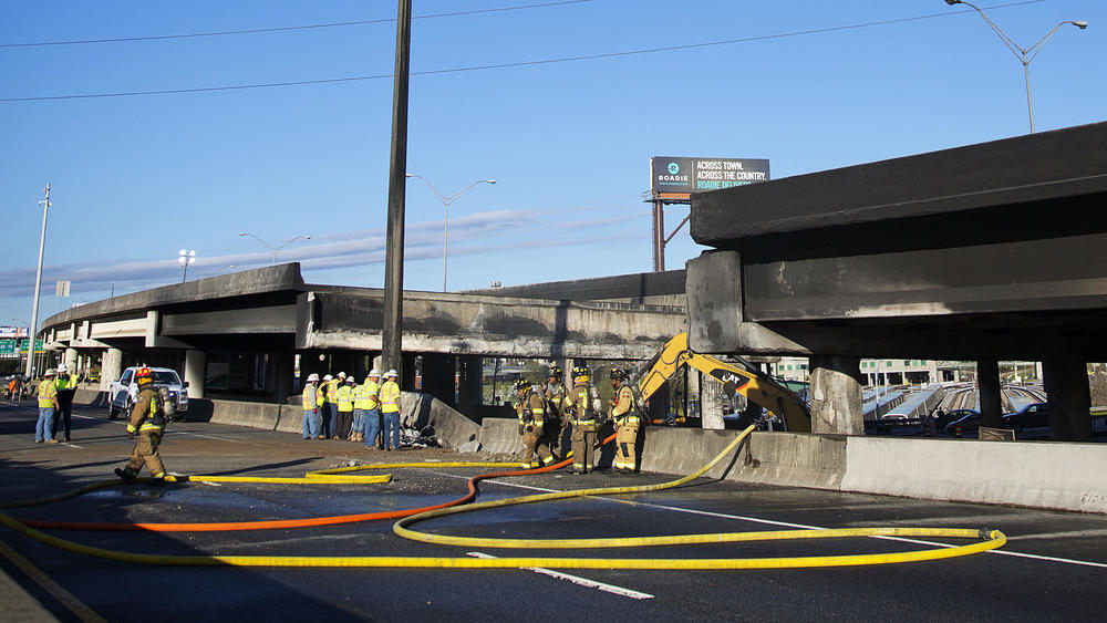 A portion of Interstate 85 that collapsed in March will reopen Monday, Georgia officials say. Here, construction workers and firefighters survey a section of the overpass that collapsed from a large fire in Atlanta.