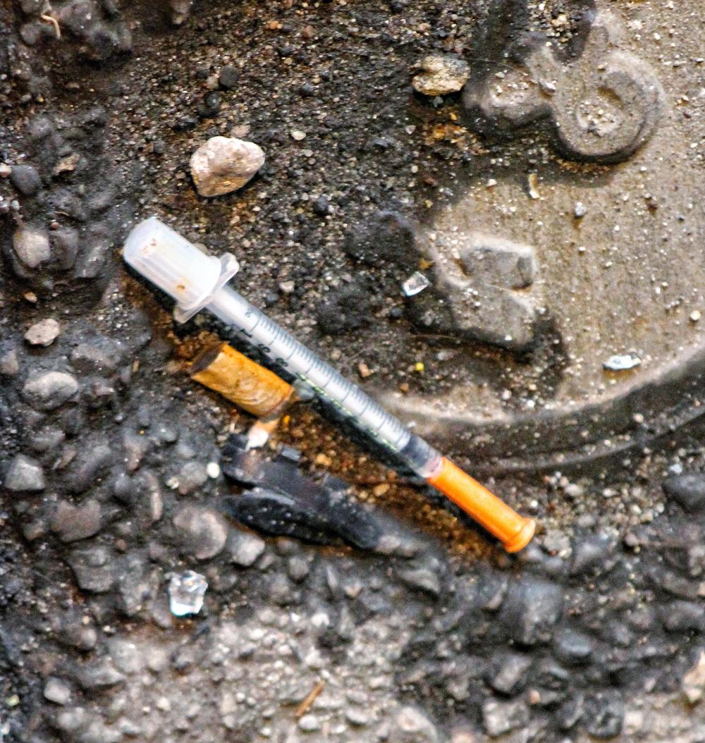 A syringe discarded in a street.