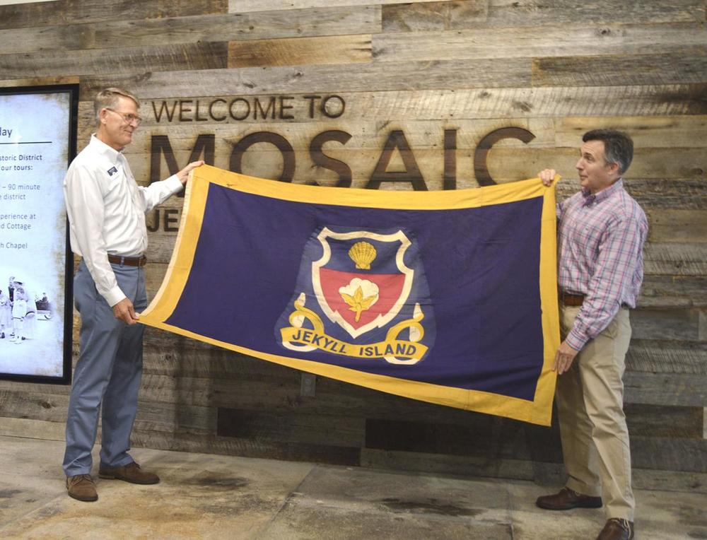 Buff Leavy, right, president and executive editor of Brunswick News Publishing Co., presents Jekyll Island's long-lost official flag to Jekyll Island Authority Executive Director Jones Hooks at the Mosaic museum on the island. 