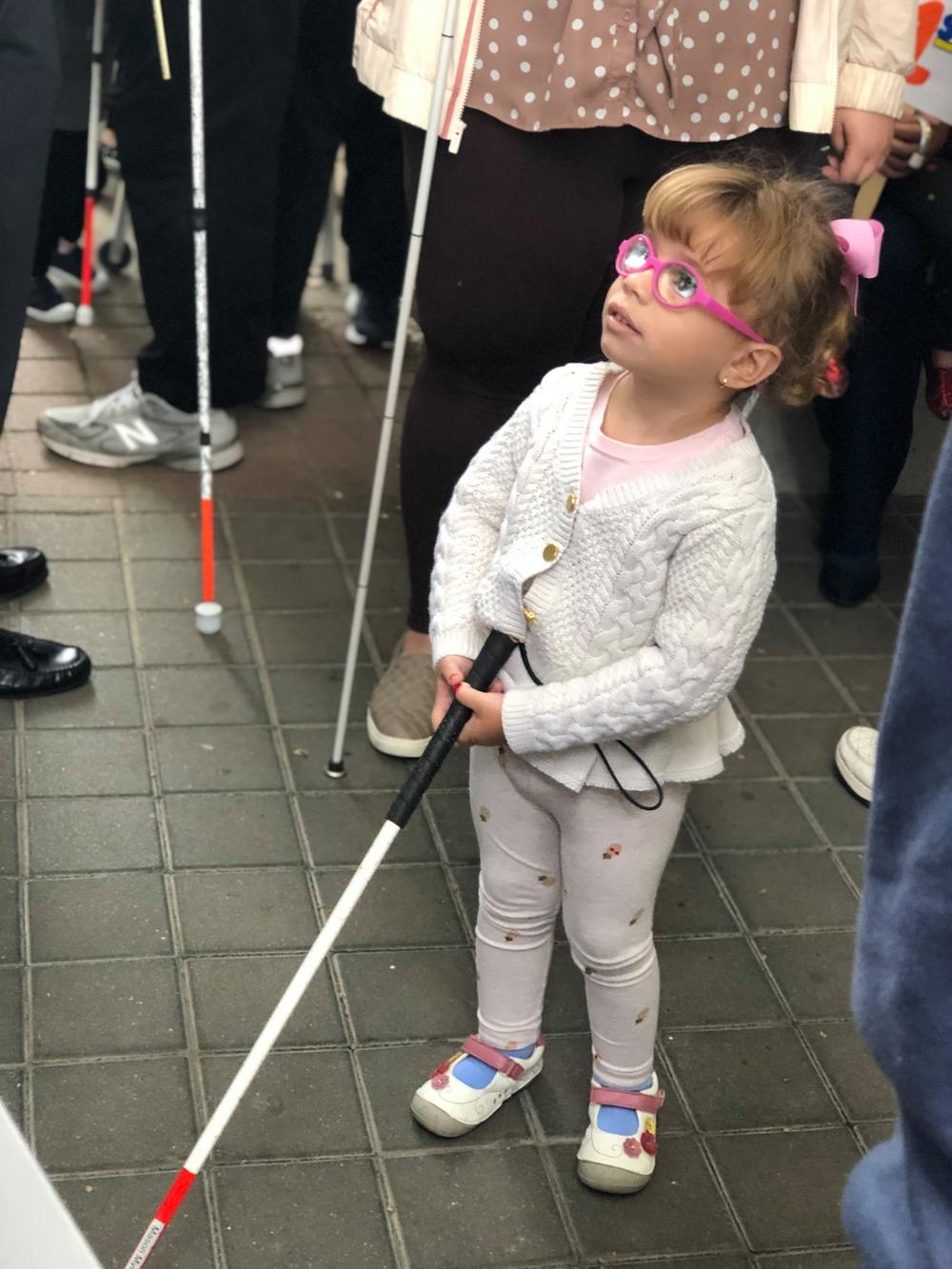 Toddler Class student holding her white cane ready to walk.
