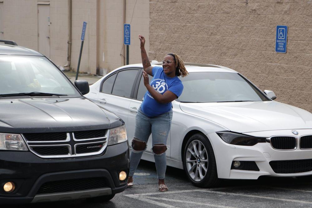 A woman praises outside her car.
