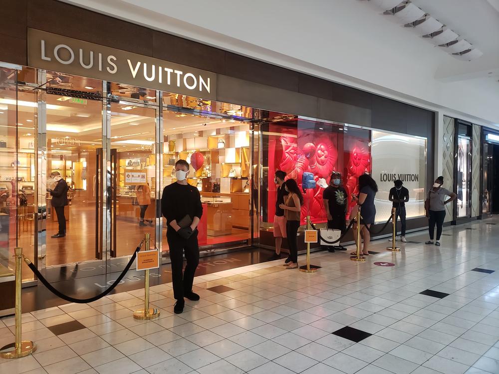 Shoppers wait to get inside the Louis Vuitton store at Lenox Square. Simon-owned malls across the state reopened on Monday. 
