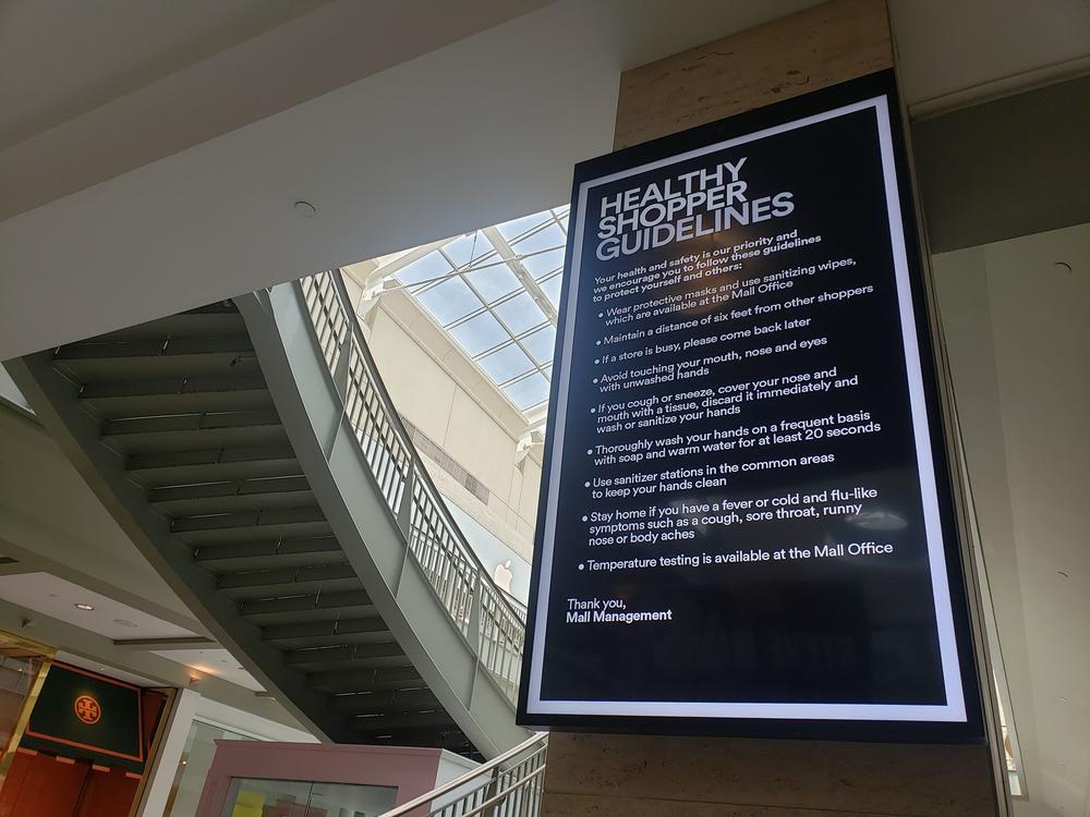 An electronic sign at Lenox Square lists social distancing safety procedures for shoppers.