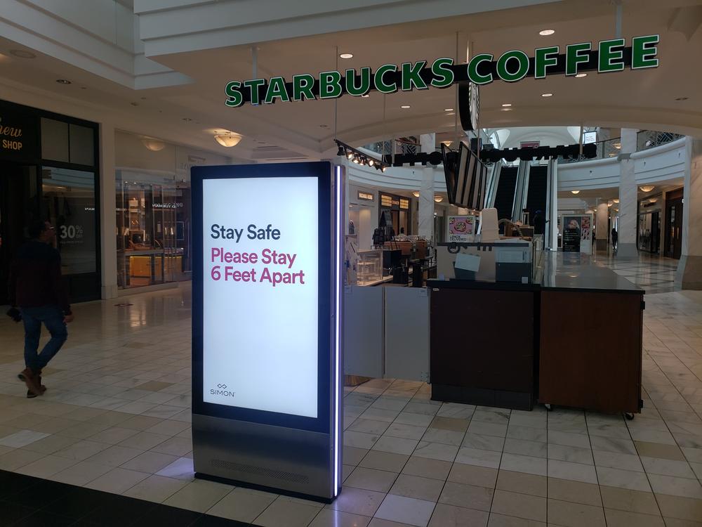 The illuminated electronic boards at Lenox Square that would usually be flashing rotating advertisements for Apple, Tiffany and Bloomingdale's now carry brightly illuminated warnings to maintain social distancing.