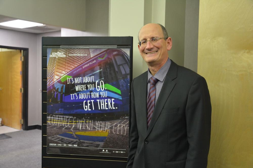 A.J. Robinson showing off a promotional poster for the Atlanta Streetcar.
