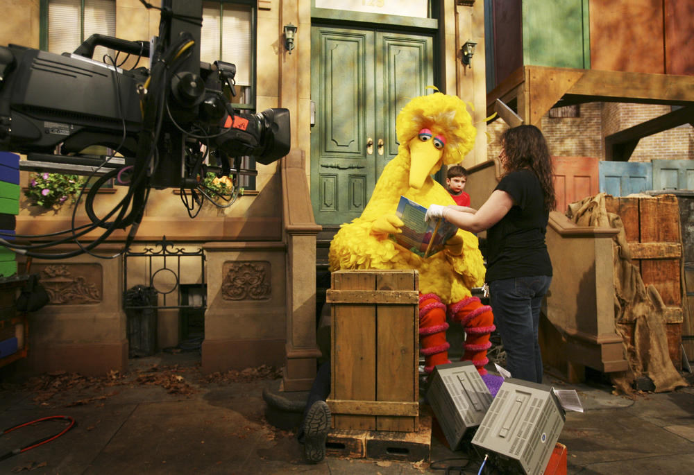 Michelle Hickey, a muppet wrangler, helps Big Bird hold a book during a rehearsal of "Sesame Street" in New York.