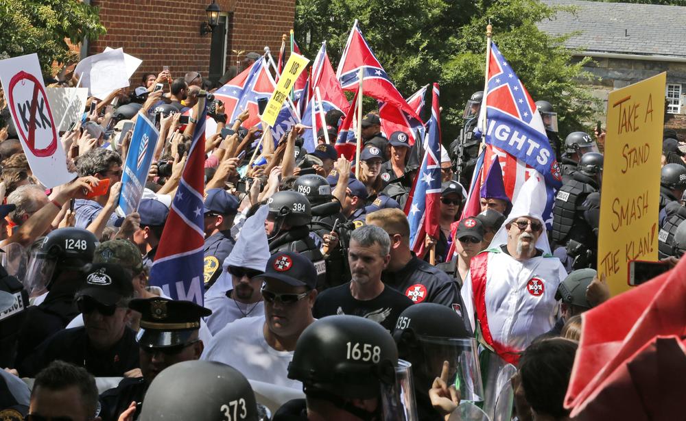Members of the KKK are escorted by police past a large group of protesters during a KKK rally Saturday, July 8, 2017, in Charlottesville, Va.