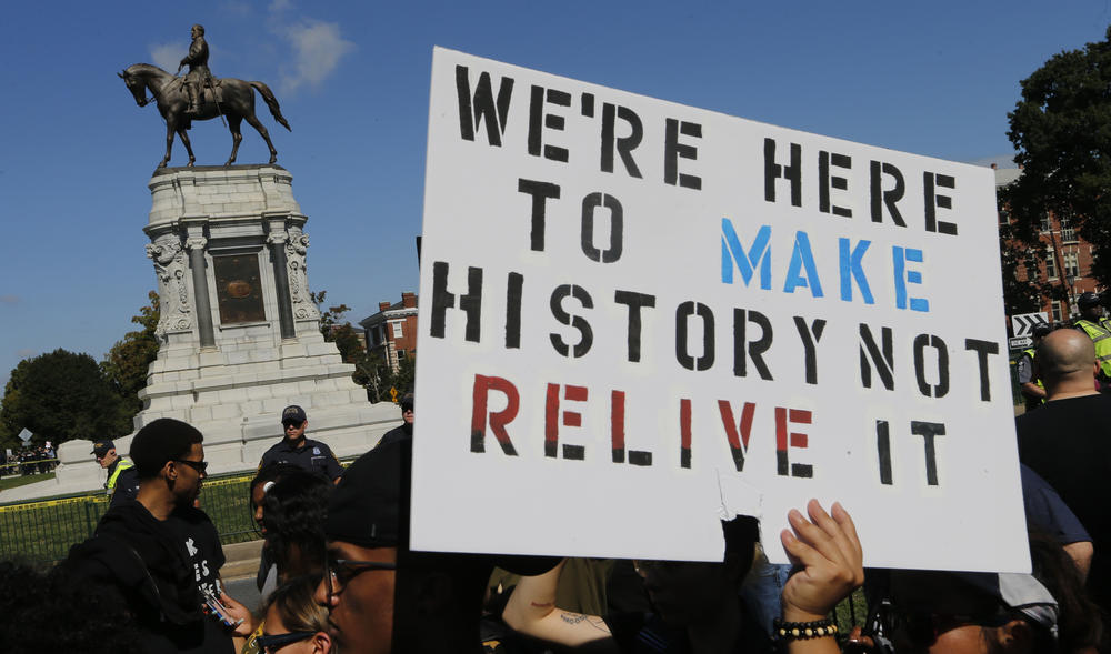 Protesters hold signs in front of the statue of Confederate General Robert E. Lee on Monument Avenue in Richmond, Va., Saturday, Sept. 16, 2017. The group of Confederate demonstrators were escorted out by police after a 50 minute protest.