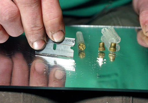 A razor blade is used to divide the contents of a five-dollar vile of crack, a smokable, purified form of cocaine, at a crack house in the South Bronx section of New York in 1989. 