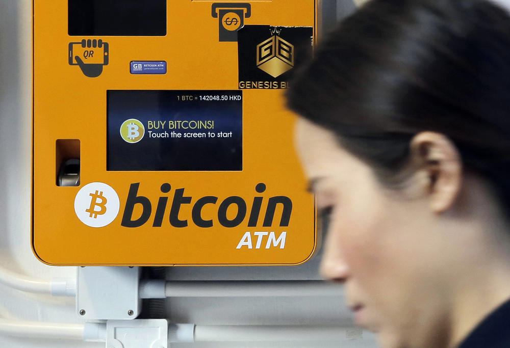 In this Dec. 21, 2017 file photo, a woman walks past the Bitcoin ATM in Hong Kong. 