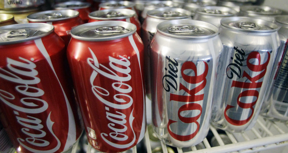 In this March 17, 2011, file photo, cans of Coca-Cola and Diet Coke sit in a cooler in Anne's Deli in Portland, Ore. The Coca-Cola Co. plans to help collect and recycle a bottle or can for every one that it sells by 2030.
