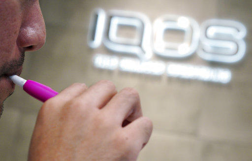In this Oct. 22, 2018 photo, a visitor tries out an iQOS at a store in Tokyo. The product launched Oct. 4, 2019, in the United States.