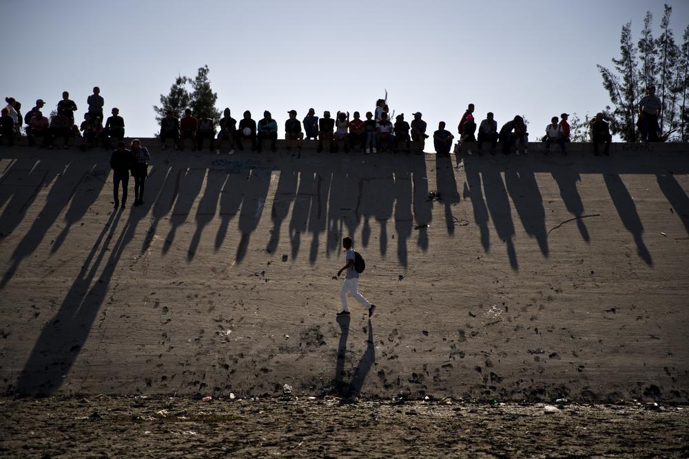 Migrants watch clashes with U.S. border agents, seen from Tijuana, Mexico.