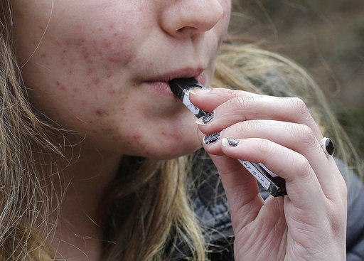 A high school student uses a vaping device. 
