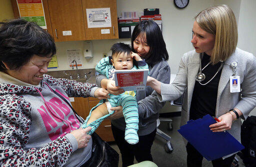 Mother Wenyi Zhang holds 1-year-old Abel Zhang moments after he received a vaccine for measles, mumps, and rubella (MMR), at the International Community Health Services Wednesday, Feb. 13, 2019, in Seattle. 